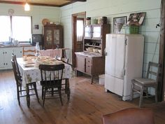 an old fashioned kitchen and dining room with wooden floors, white walls, and wood trimming