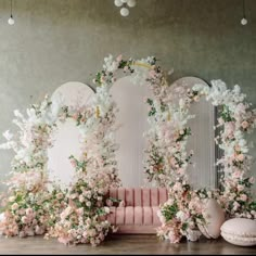 a pink couch with flowers on it in front of a mirror