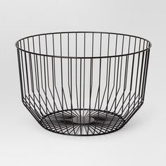 a black wire basket with a small metal object in the center on a white background