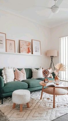 a living room with green couches and pictures on the wall above it's coffee table