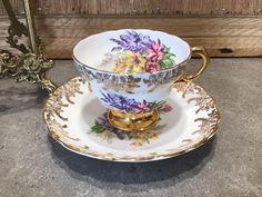 a cup and saucer with flowers painted on the side, sitting on a table