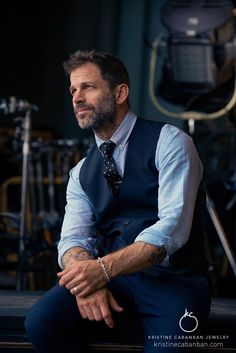 a man in a vest and tie sitting down