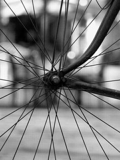 the spokes on this bicycle are very close to the ground, and it is black and white