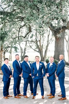 a group of men standing next to each other in front of a large oak tree