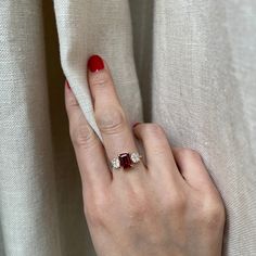 a woman's hand with a ring on top of her finger, next to a curtain