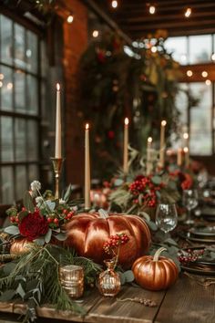 a wooden table topped with pumpkins and greenery next to candles on top of it