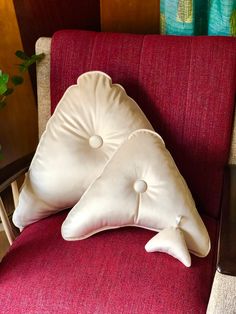 two white pillows sitting on top of a red chair