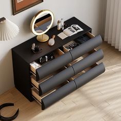 a black and gold sideboard with magazines on it next to a lamp, mirror and fan