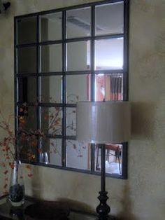 a mirror is hanging on the wall above a table with a lamp and vases