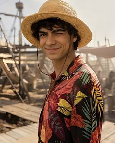 a young man wearing a straw hat standing on a wooden dock with boats in the background