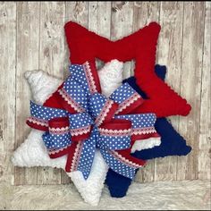 three red, white and blue bows are hanging on a wooden wall next to a teddy bear