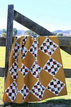 a quilt is hanging on a fence post