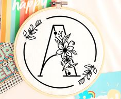 an embroidery pattern with the letter a and flowers on it, surrounded by other crafting supplies