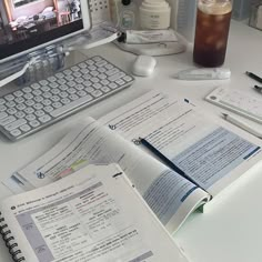 an open book sitting on top of a desk next to a computer monitor and keyboard