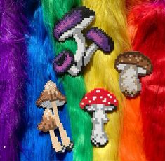 several different types of mushroom brooches are displayed on colored fur, and one is multicolored