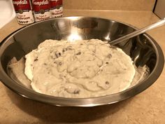 a metal bowl filled with batter next to two cans of campbell's cream cheese