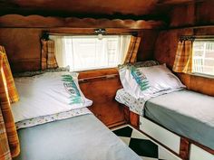 two beds in a small room with checkered flooring on the walls and windows