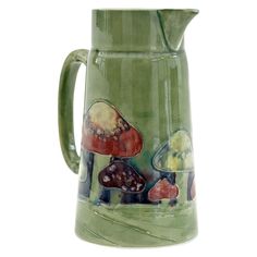 a green pitcher with mushrooms painted on it