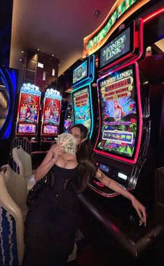 a woman in a black dress is playing slot machines