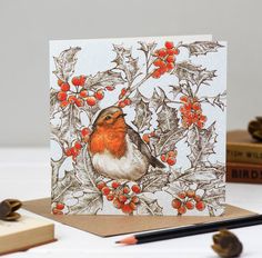 a card with a bird sitting on a tree branch surrounded by red berries and leaves