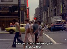 a group of people walking across a street next to tall buildings with a red arrow above them