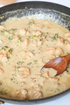 shrimp and broccoli are being cooked in a skillet with a wooden spoon