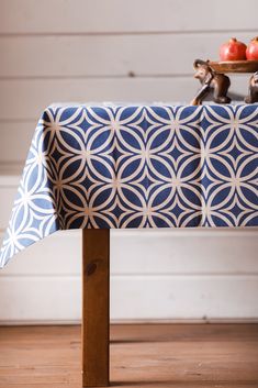 a blue and white patterned table cloth on a wooden chair with apples in the background