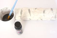 a toothbrush in a cup next to a stone wall and paint roller on the floor