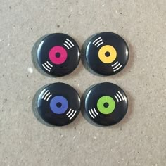 three buttons with different colors on them sitting on the floor next to each other in front of a white wall