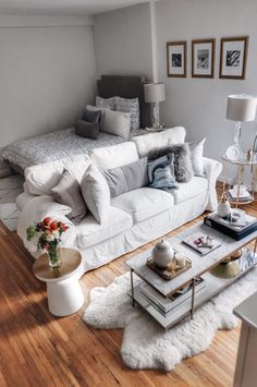 a living room filled with white furniture and lots of pillows on top of it's couches