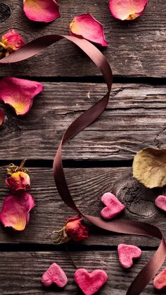 rose petals and ribbon on wooden surface with heart - shaped objects in the middle, top view