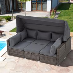 an outdoor couch with cushions on it next to a swimming pool