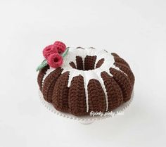 a crocheted bundt cake with icing and a single flower on top