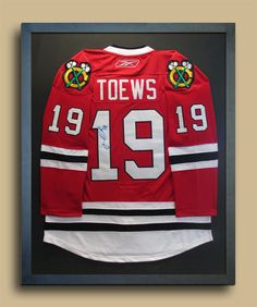 an autographed hockey jersey hangs in a framed frame