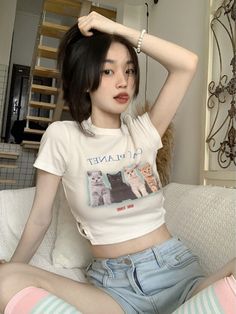 a woman sitting on top of a white couch next to a cat t - shirt