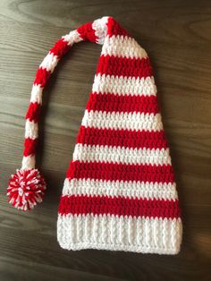 a red and white striped knitted hat with pom - pom on top