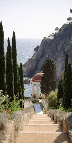 the steps lead up to an outdoor gazebo near some trees and water with mountains in the background