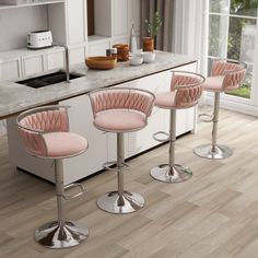 three pink bar stools sitting in front of a counter