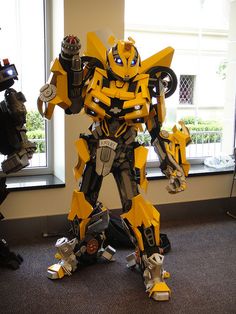 a yellow and black robot standing in front of a window