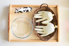 a basket with two plastic hand puppets and a glass bowl on it, next to a cow figurine