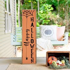 a wooden sign sitting on top of a porch next to a basket filled with pumpkins