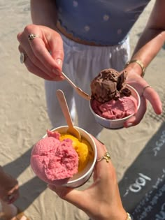 two people holding bowls of ice cream on the beach