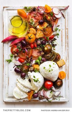 a white plate topped with lots of different types of vegetables and fruit on top of each other