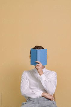 a person sitting down with a book over their head by jodi lenski for stocksy photography