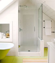 an attic bathroom with green flooring and white walls, along with a walk in shower