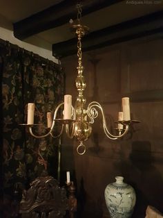 a chandelier hanging from the ceiling next to a vase with candles on it