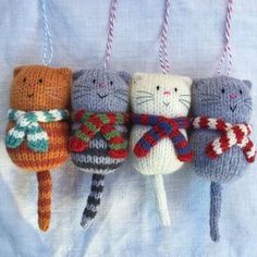 four knitted cats hanging from strings on a bed