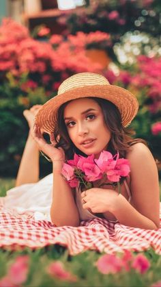 a beautiful woman laying on top of a checkered blanket with flowers in her hand