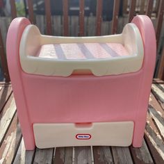 a pink and white toy oven sitting on top of a wooden deck