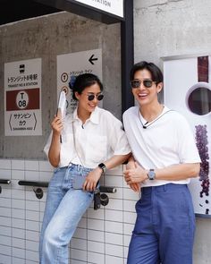 two people standing next to each other in front of a building